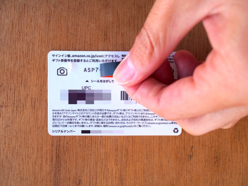 Amazonギフト券グリーティングカードタイプのメッセージカードの中にあるカードタイプのAmazonギフト券の保護シールをはがすところ
